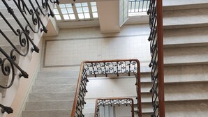 Een marmeren trap met versierde zwarte metalen leuningen en een houten handrail.