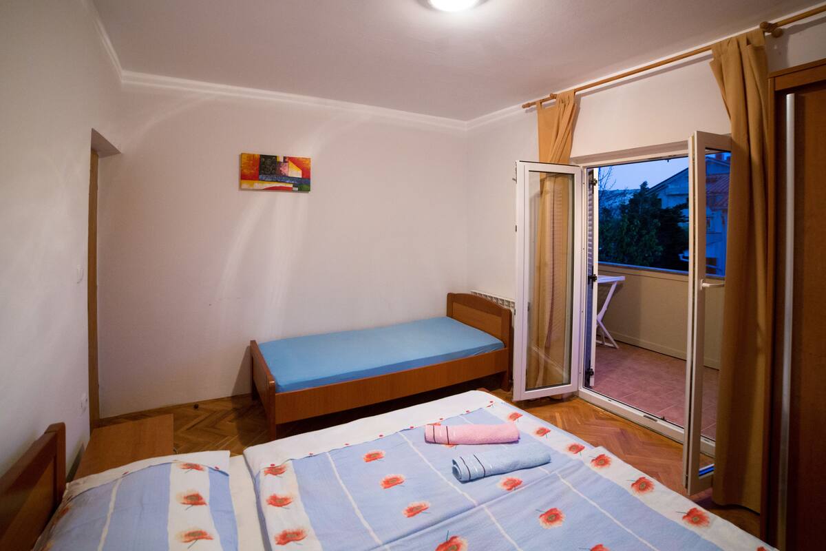 Ein kleines Schlafzimmer mit einem Einzelbett, einem kleinen Tisch und einer Schiebetür, die auf einen Balkon führt.