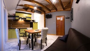 A cozy living area with a sofa, a dining table with chairs, a kitchen with green cabinets, and a wooden ceiling. - Apartments Sanic 518 (Lopar)