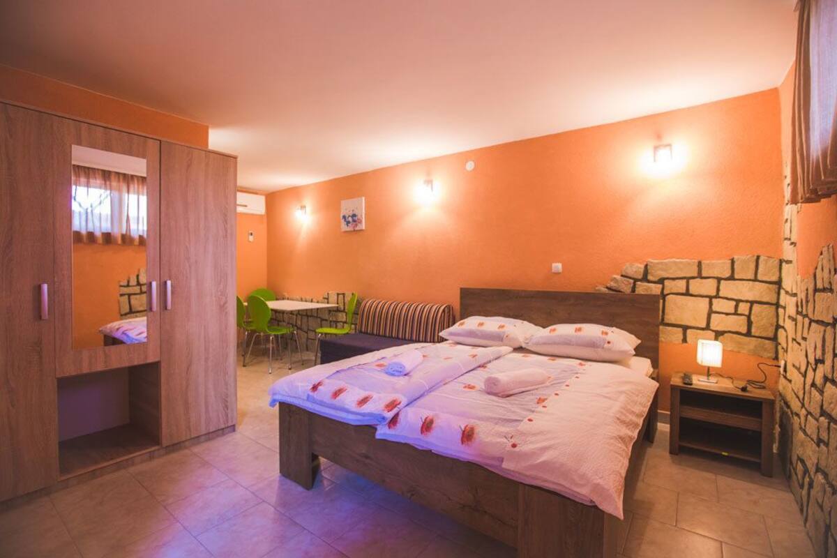 Ein Schlafzimmer mit einem Bett, einem Holzschrank, einem kleinen Tisch mit Lampe und einer Steinwand.