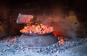 A metal container filled with glowing coals and embers, surrounded by a brick wall.