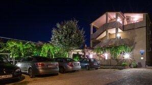 A parking area with several cars, a building with balconies, and a tree in the background. - Apartments Sanic 518 (Lopar)