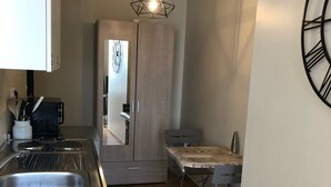 Et kompakt køkken med indbygget komfur, vask og spiseplads med bord og stole.