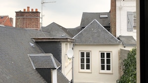 En smal passage mellem bygninger med et lille haveområde, et hvidt hus med et gråt tag og en murstens skorsten.