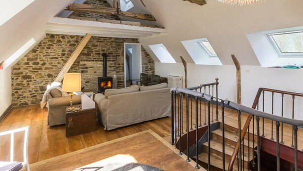Ein Schlafzimmer im Loft-Stil mit Steinwand, Kamin, Sofa und Treppe.
