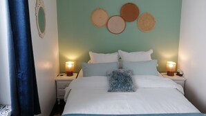 Quarto com cama, duas mesas de cabeceira com luminárias, luminária pendente e decoração nas paredes.