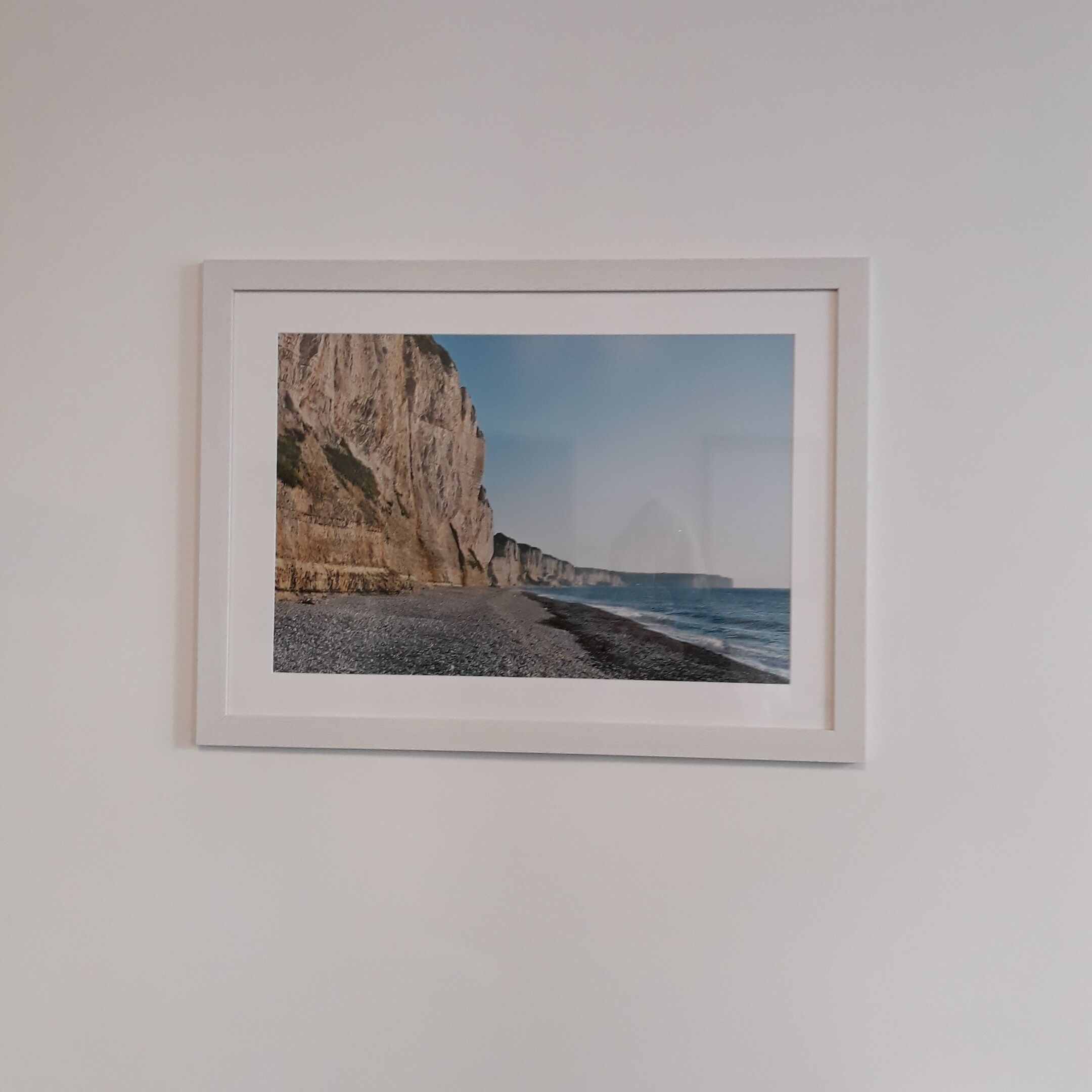 A framed photograph of a coastal landscape with cliffs and the sea.