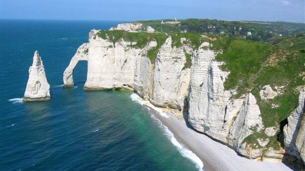 Paisagem costeira com falésias brancas e uma praia arenosa.