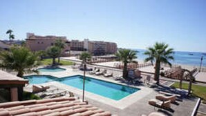 Un complexe hôtelier doté d’une piscine, de palmiers et offrant une vue sur l’océan.