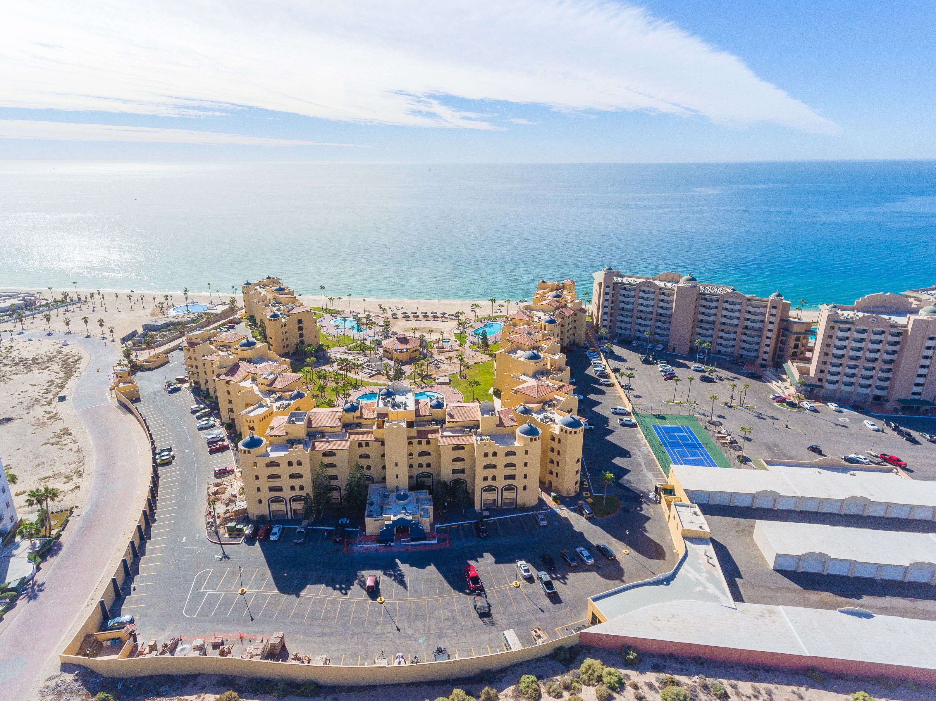 A resort with multiple buildings, a pool area, and a beach.