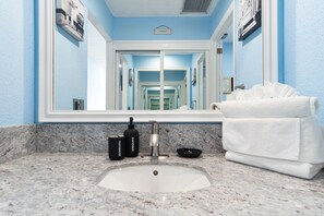 Ein Badezimmer mit Marmorwaschbecken, einem Handtuch und einem Spiegel, der einen Flur reflektiert.