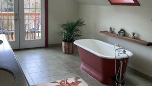 Un baño con bañera independiente, una planta en maceta, ducha y tragaluz.
