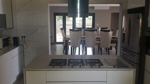 Une cuisine moderne dotée d’un îlot central, d’une cuisinière à gaz intégrée et d’appareils électroménagers en acier inoxydable.