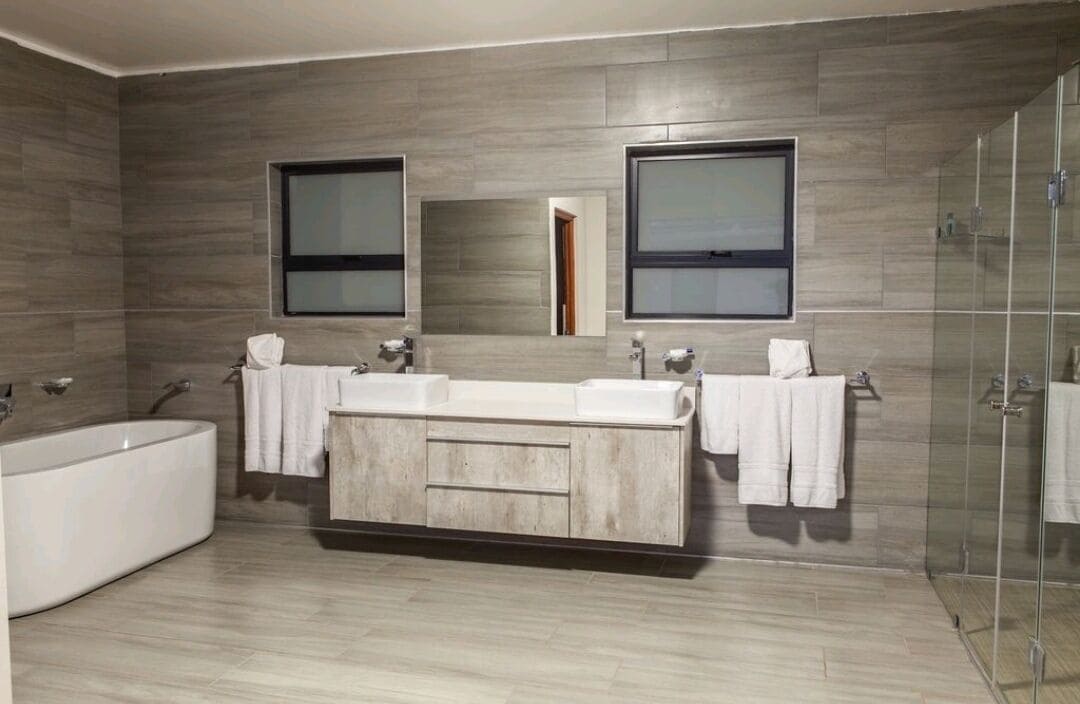 A modern bathroom with a large freestanding bathtub, a double sink vanity, and a glass-enclosed shower.