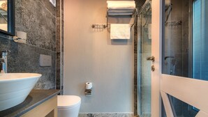 A modern bathroom with a marble sink, toilet, and shower area. - Isola12 (Kas)