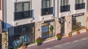 A modern hotel with a stone facade, multiple balconies, and a storefront named "The Grida Travel". - Isola12 (Kas)