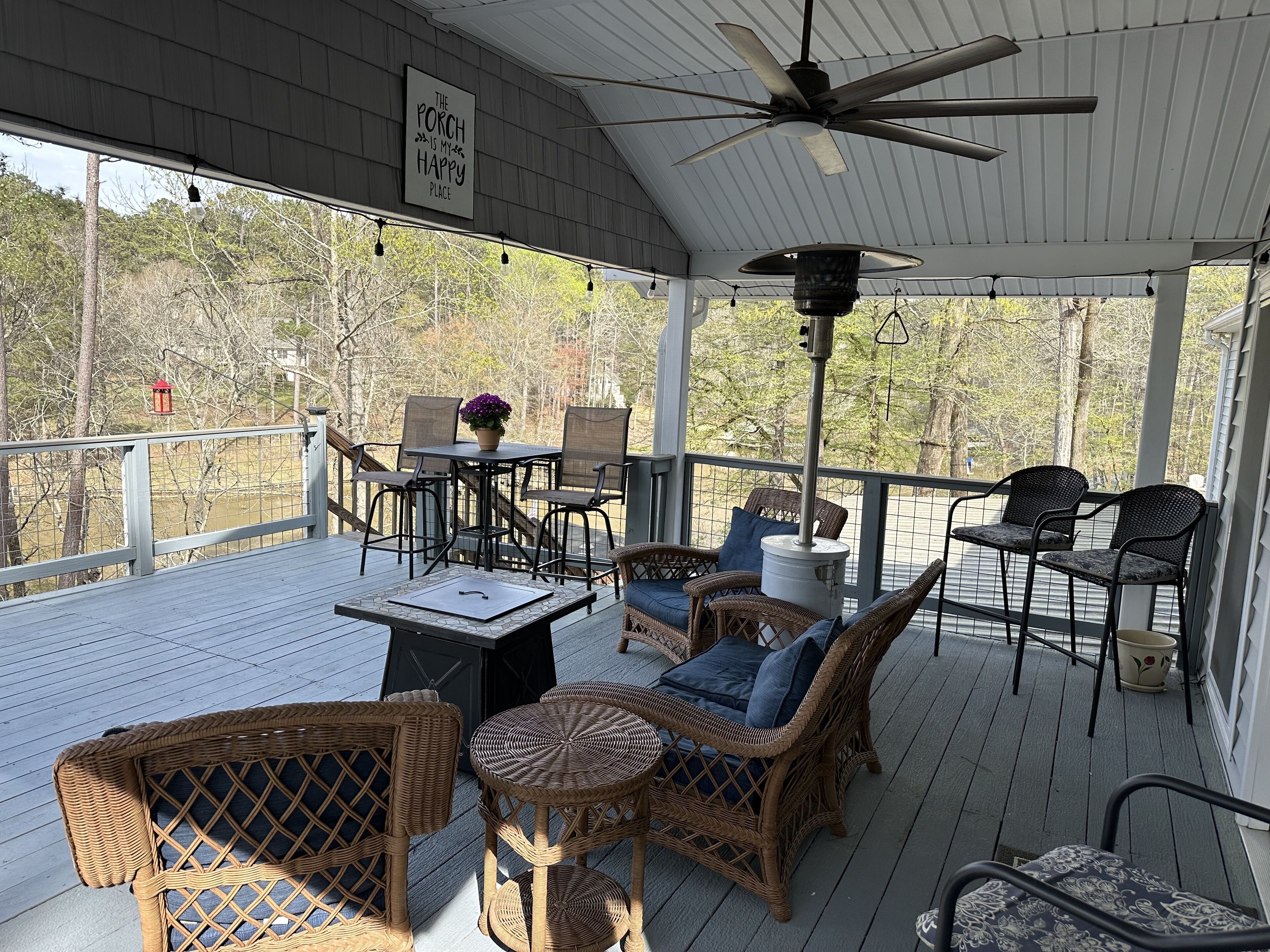 A covered outdoor patio with wicker furniture, a table, and a ceiling fan.