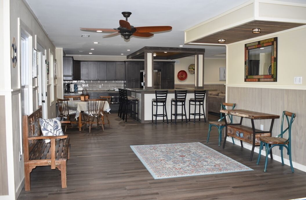 A spacious kitchen with dark wood cabinets, a central island with bar stools, and a ceiling fan.