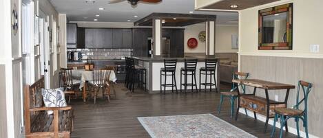 A spacious kitchen with dark wood cabinets, a central island with bar stools, and a ceiling fan.