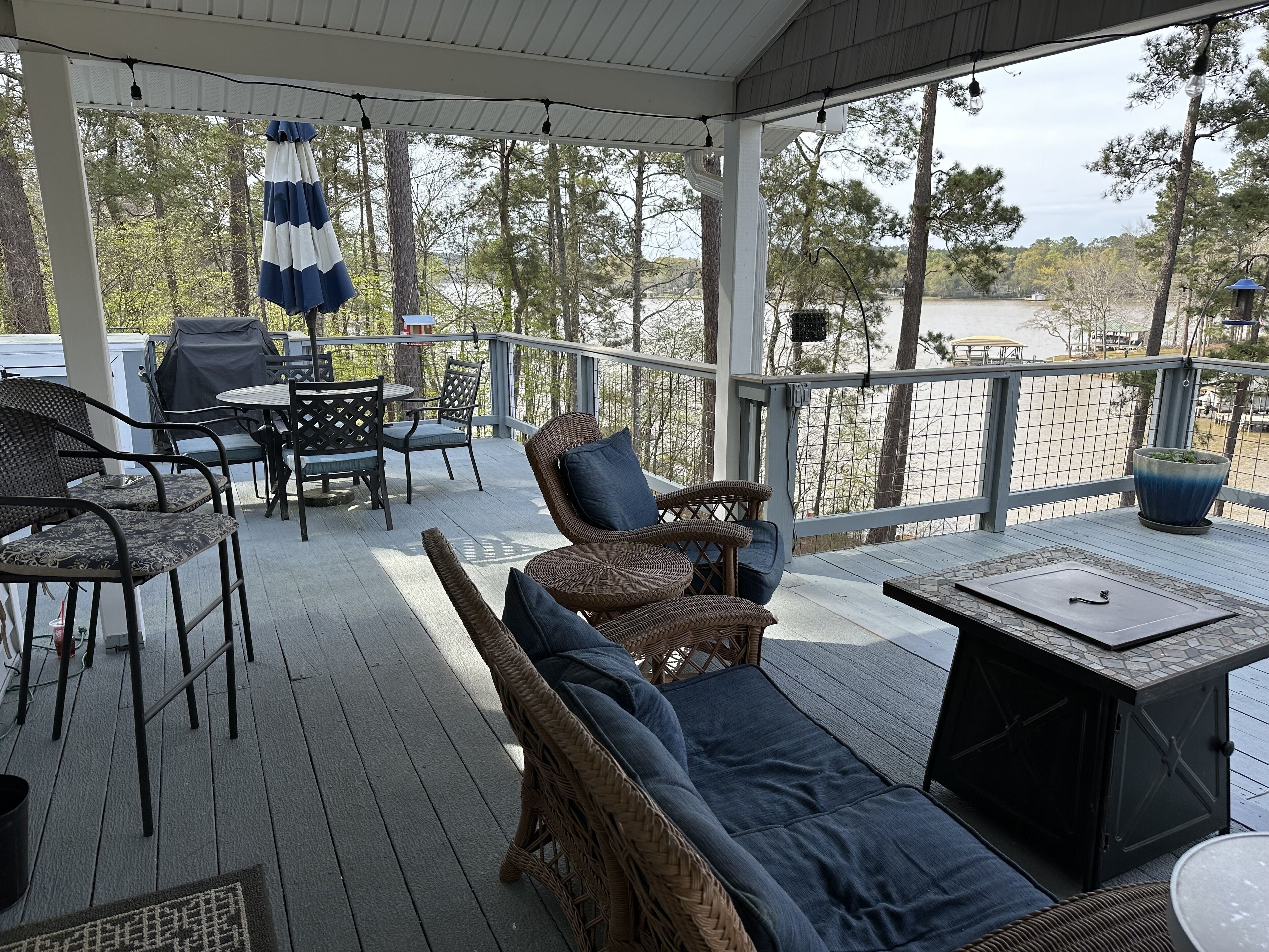 Een overdekt terras met rieten meubels, een tafel en een barbecue.