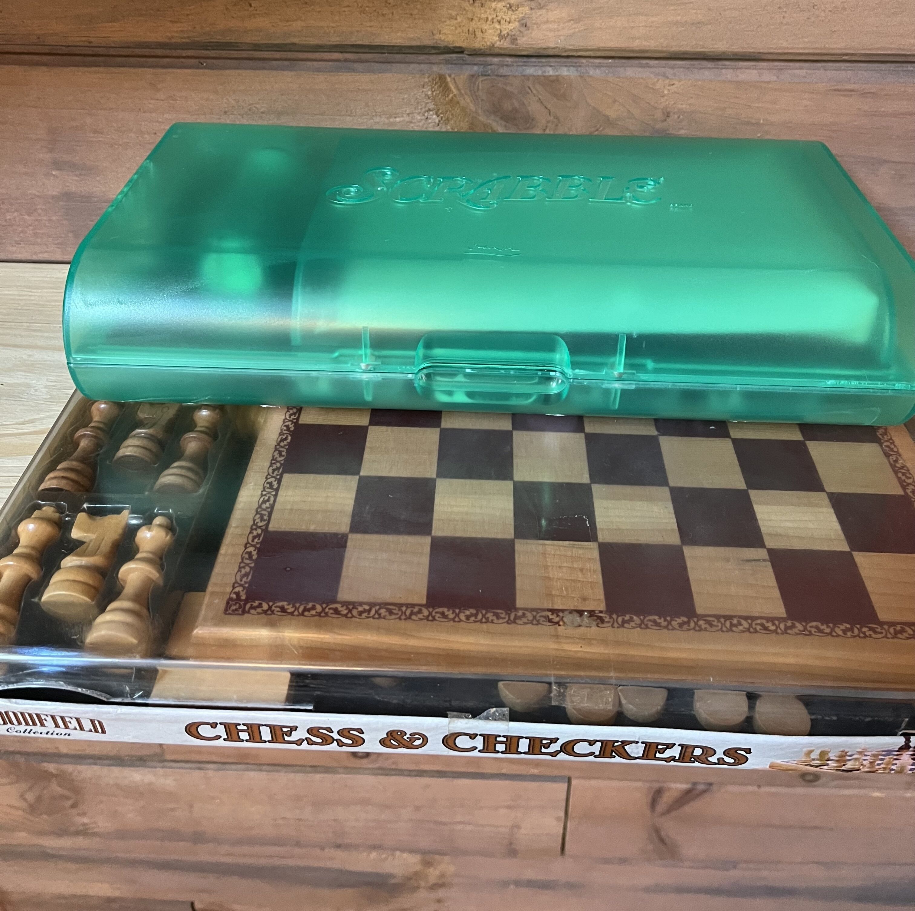Um conjunto de xadrez com tabuleiro quadriculado e peças de madeira, embalado em uma caixa verde.