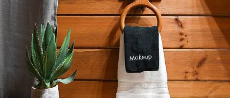 Een houten wand met een handdoekhouder waarop een handdoek ligt met de tekst 'Makeup'.
