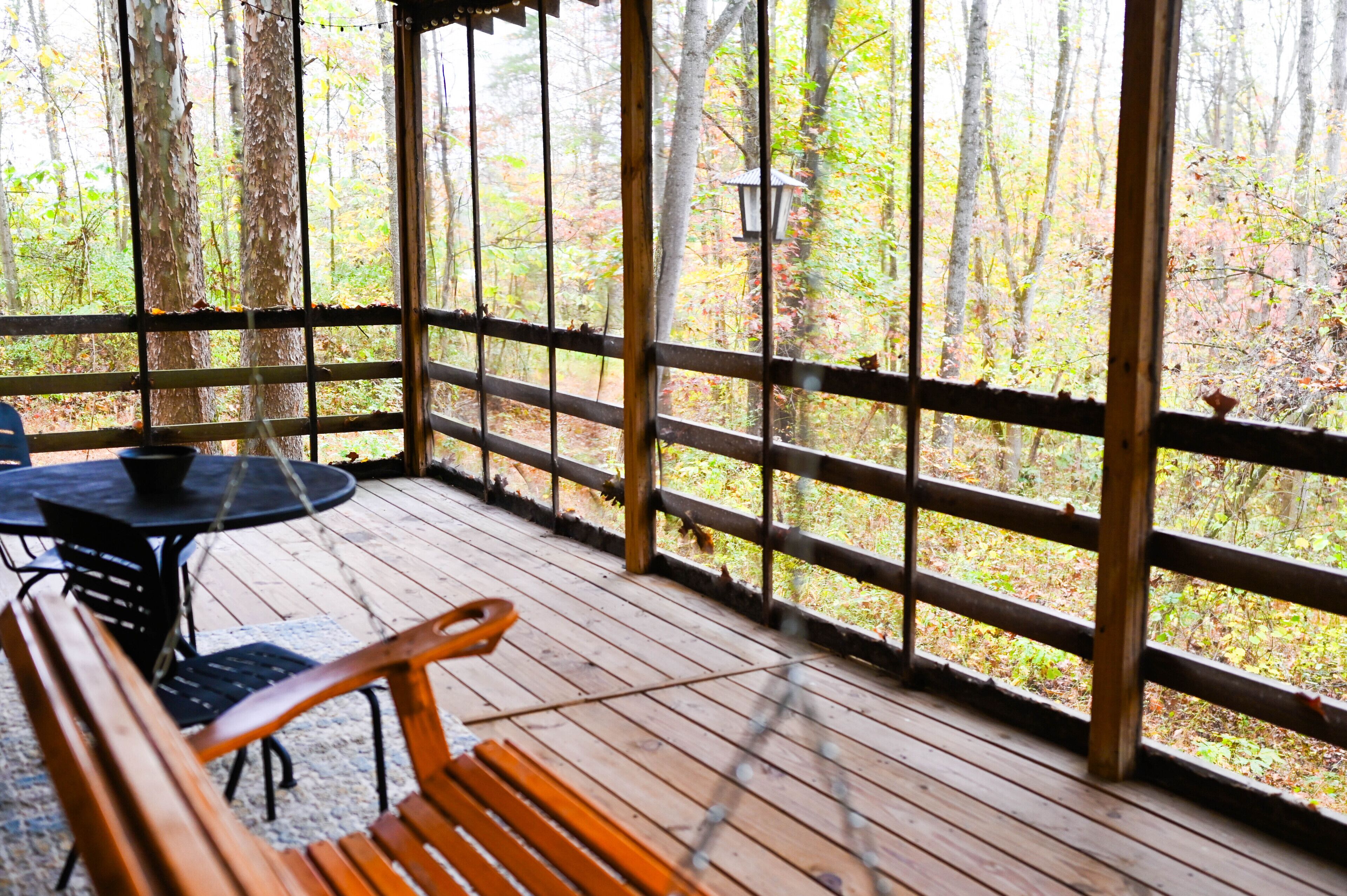 A wooden deck with a table and chairs, surrounded by a metal railing.