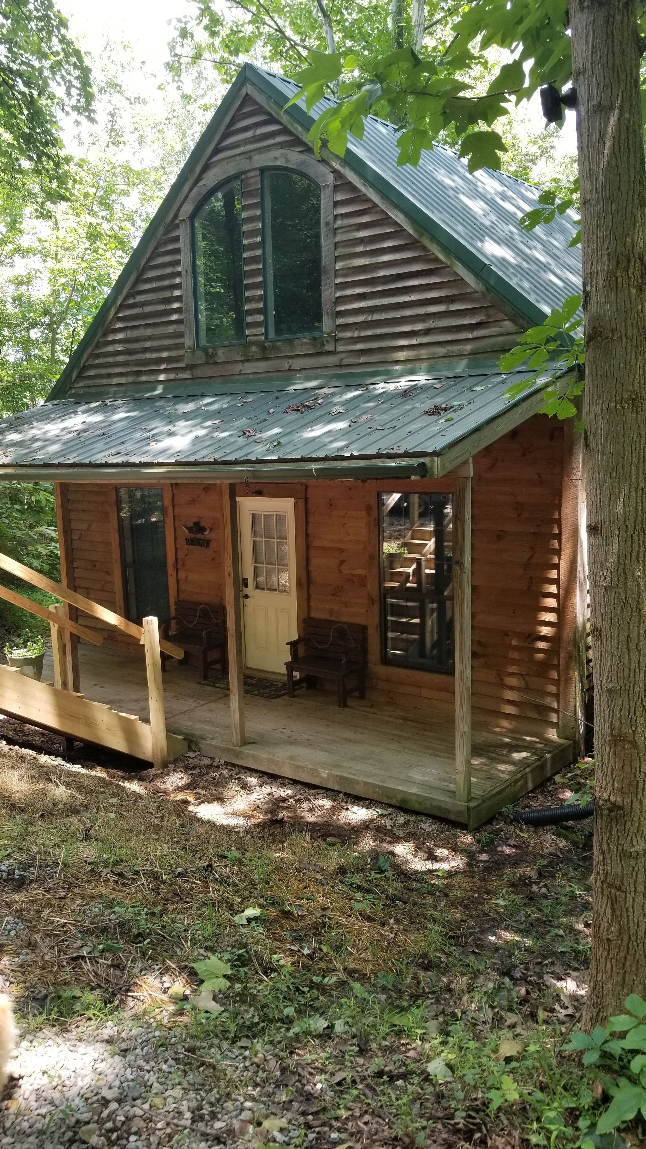 A wooden cabin with a porch, a door, and a window.