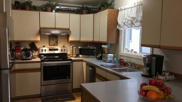 Compact kitchen with stove, microwave, oven, sink, and coffee maker for basic meal preparation.