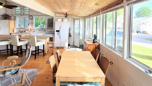 A spacious kitchen with wooden cabinets, a dining area with a long table and chairs, and large windows offering a view of the outside. - Come Relax In This Spacious 3 Bedroom Cottage, Lake Views On Both Sides. (Colchester)
