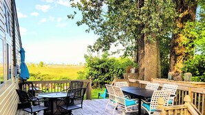 A wooden deck with outdoor furniture, including a table and chairs, overlooking a green landscape. - Come Relax In This Spacious 3 Bedroom Cottage, Lake Views On Both Sides. (Colchester)
