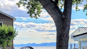 A lakeside property with a covered patio, a car, and a house. - Come Relax In This Spacious 3 Bedroom Cottage, Lake Views On Both Sides. (Colchester)