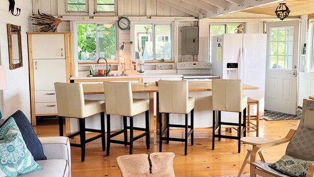 A spacious kitchen with a central island, wooden flooring, and a dining area with four chairs. - Come Relax In This Spacious 3 Bedroom Cottage, Lake Views On Both Sides. (Colchester)