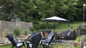 A backyard patio with Adirondack chairs, a table, and a grill. - Beautiful 4br home, village of Bolton Landing. Great location! Walk everywhere! (Bolton Landing)