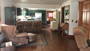 A spacious living room with a wooden floor, a large brown leather armchair, a wooden coffee table, and a patterned rug. - Beautiful 4br home, village of Bolton Landing. Great location! Walk everywhere! (Bolton Landing)
