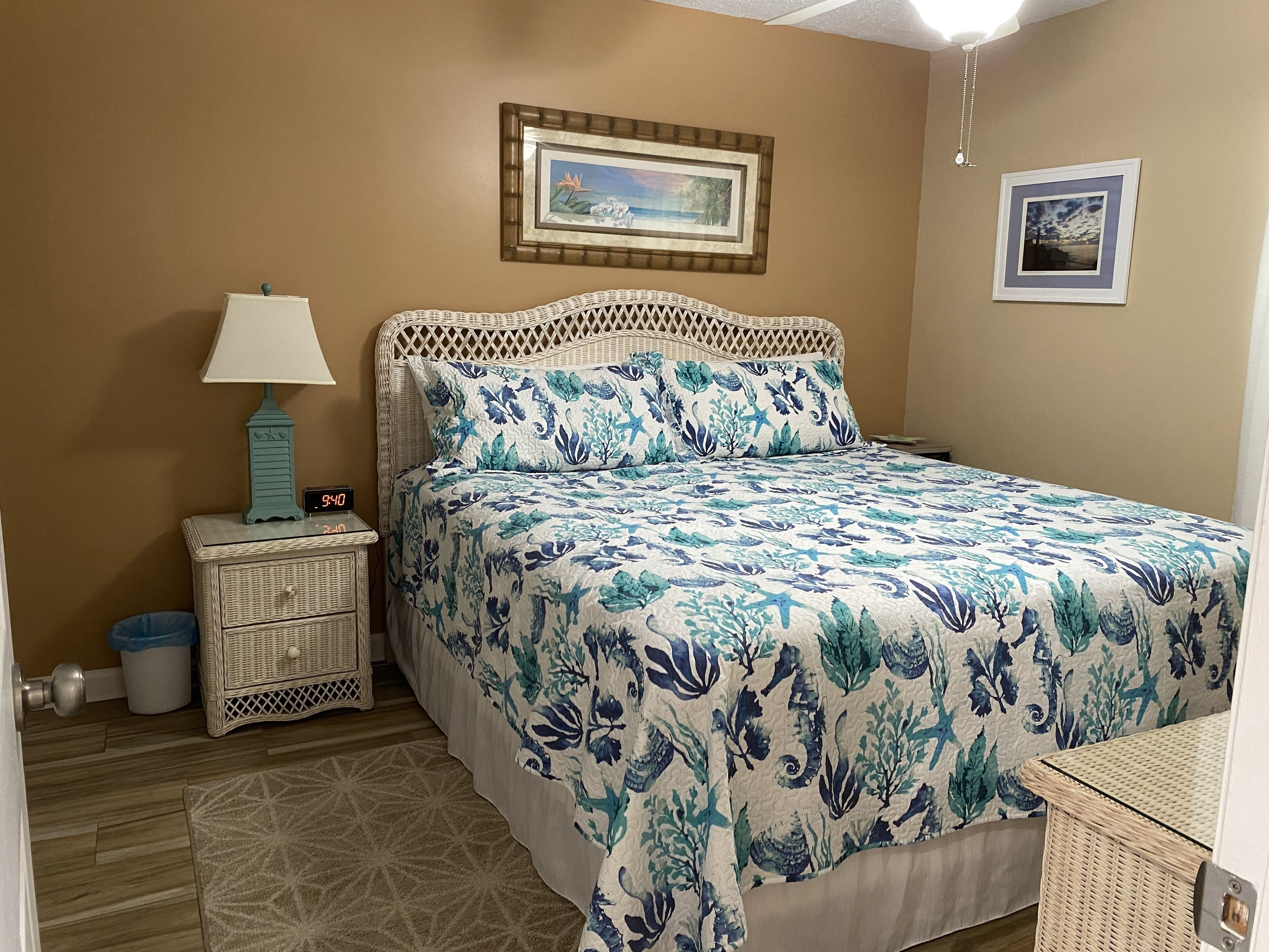 A bedroom with a bed, a nightstand, a lamp, and a wall clock.