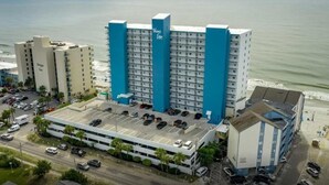 Un hôtel de grande hauteur, avec de nombreux étages, un parking et une vue sur la plage.