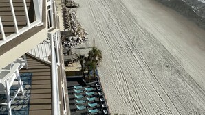Un hôtel situé en bord de mer, doté d’une piscine, de chaises longues et offrant une vue sur l’océan.