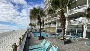 Un hôtel situé en bord de mer, doté d’une piscine, de chaises longues et offrant une vue sur la plage.