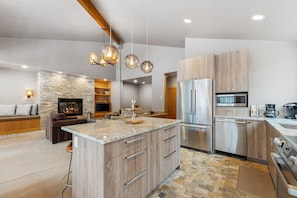 A modern kitchen with a central island, stainless steel appliances, and a stone accent wall.