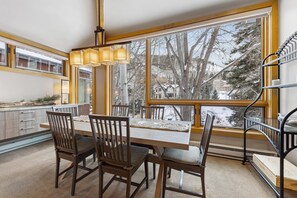 A dining area with a large window, wooden chairs, and a table.
