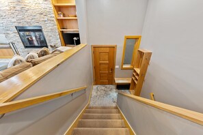 Un escalier avec des rampes en bois menant à une porte, un mur en pierre et une cheminée.