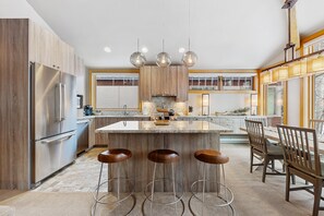 Une cuisine moderne dotée d’un îlot central, de tabourets de bar et d’un coin repas avec des chaises en bois.