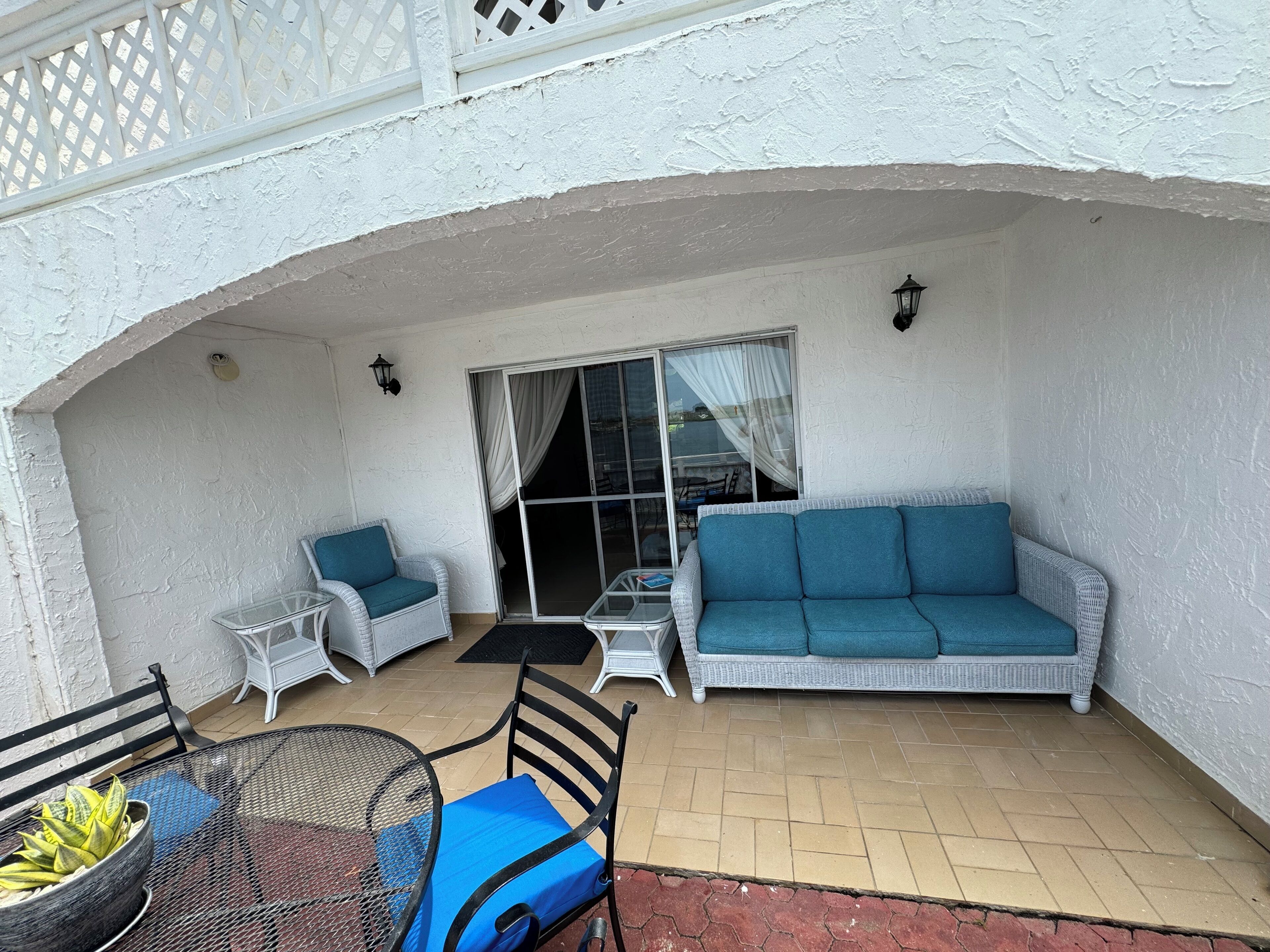 Un patio couvert comprenant un canapé en osier, une petite table et une chaise.