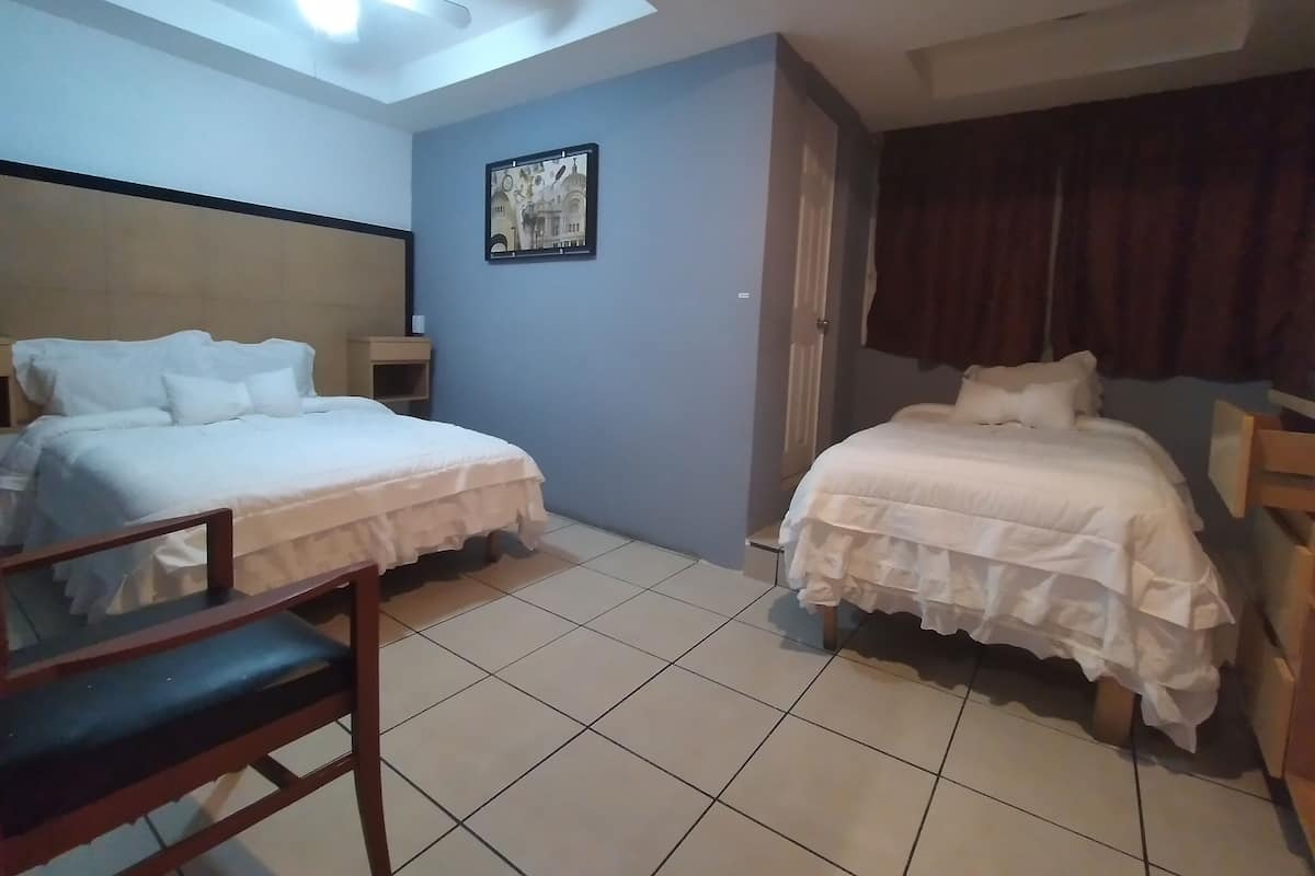 A hotel room with two beds, a desk, and a chair.