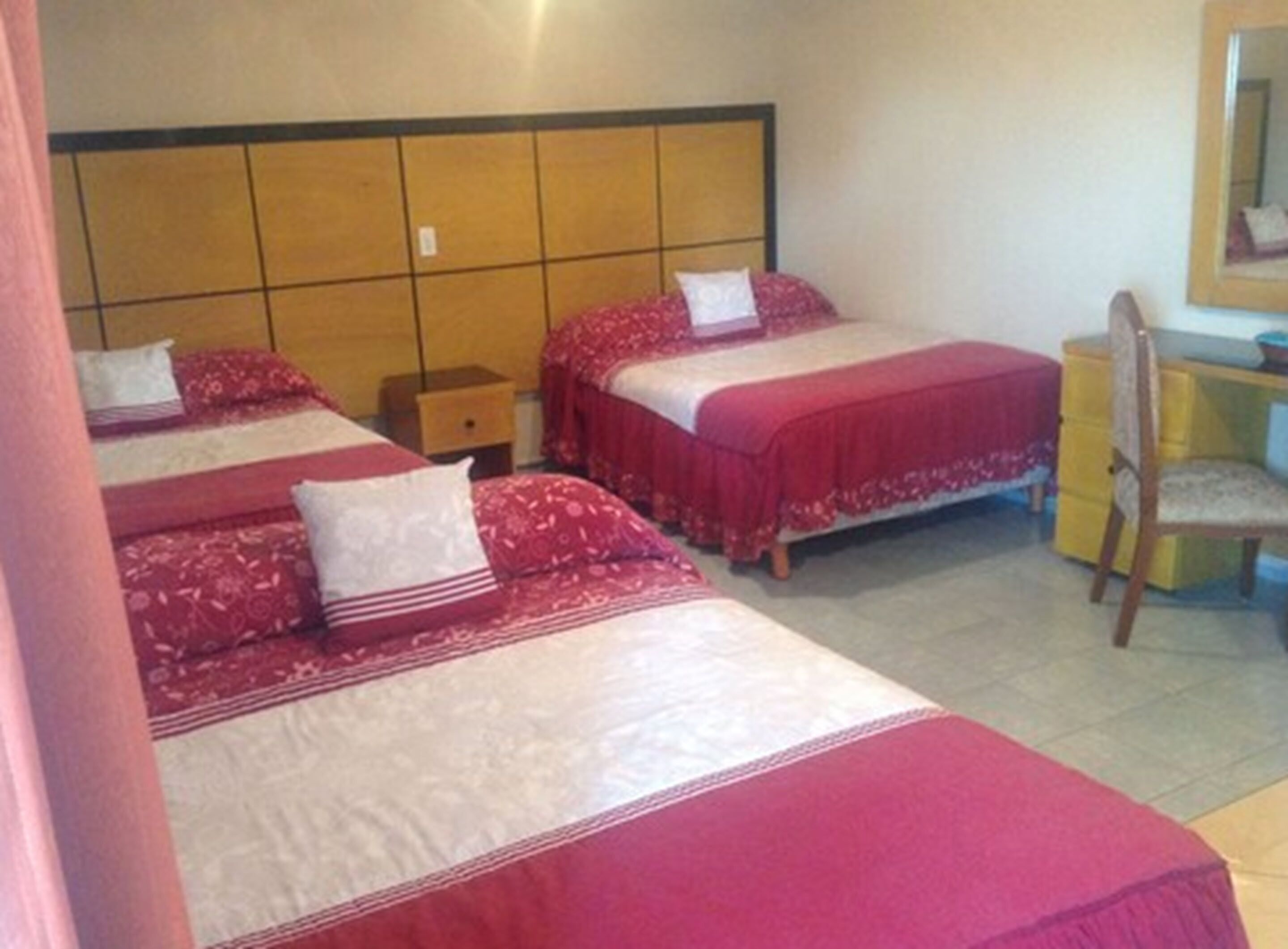 A hotel room with two beds, a desk, and a chair.