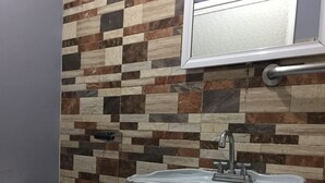 Une salle de bain avec un mur carrelé, un lavabo blanc et des toilettes.