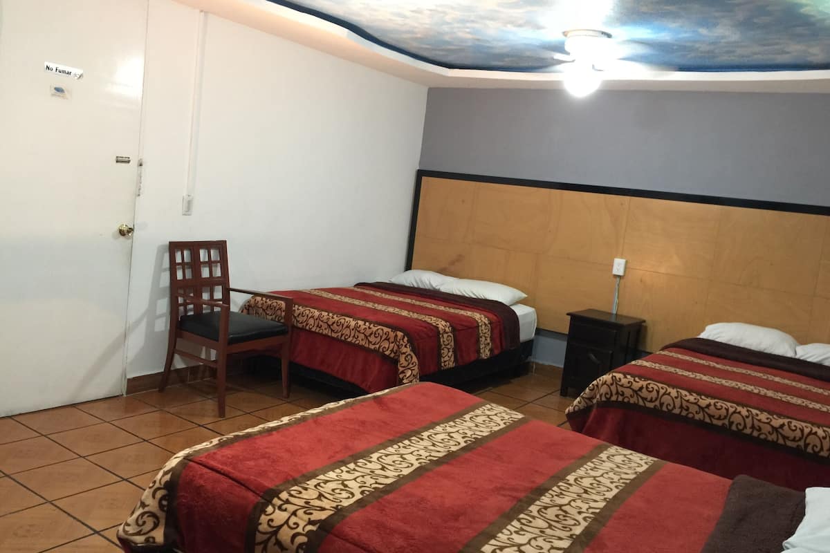 A hotel room with two beds, a chair, a nightstand, and a ceiling with a light fixture.