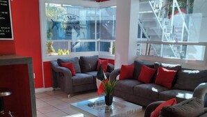 Een moderne hotellobby met twee grijze banken, een salontafel en een receptiebalie.