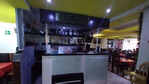 Een restaurant met een bar, tafels en stoelen.
